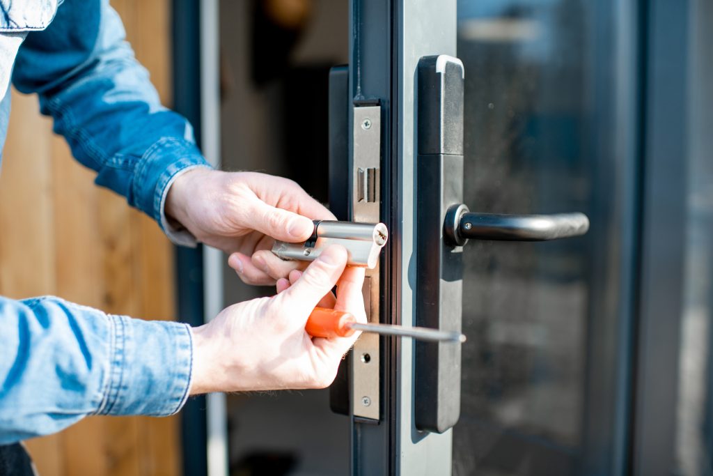 Professional locksmith installing high-security commercial lock system on glass storefront door for Miami business